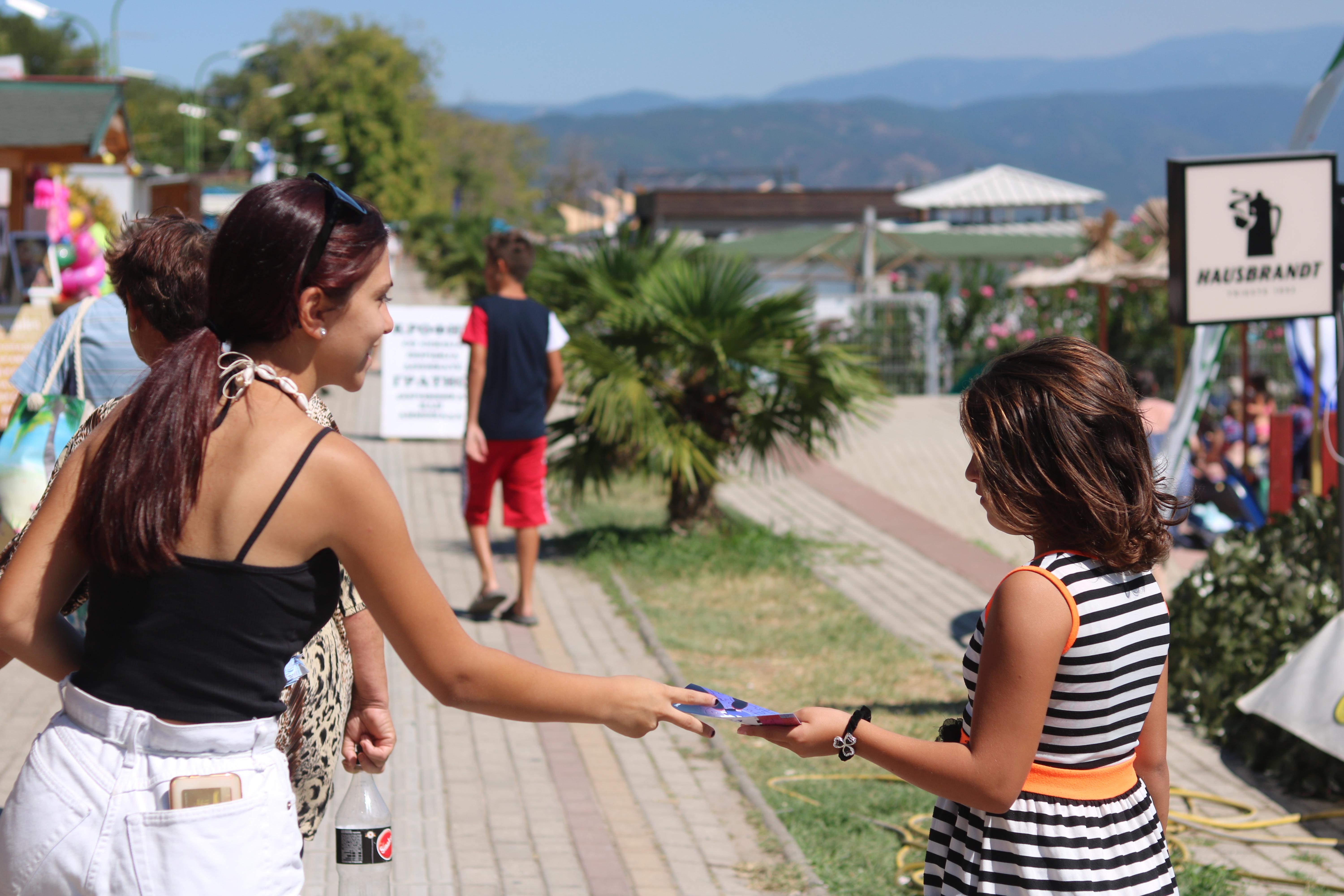 A young woman handling a leaflet to another woman 