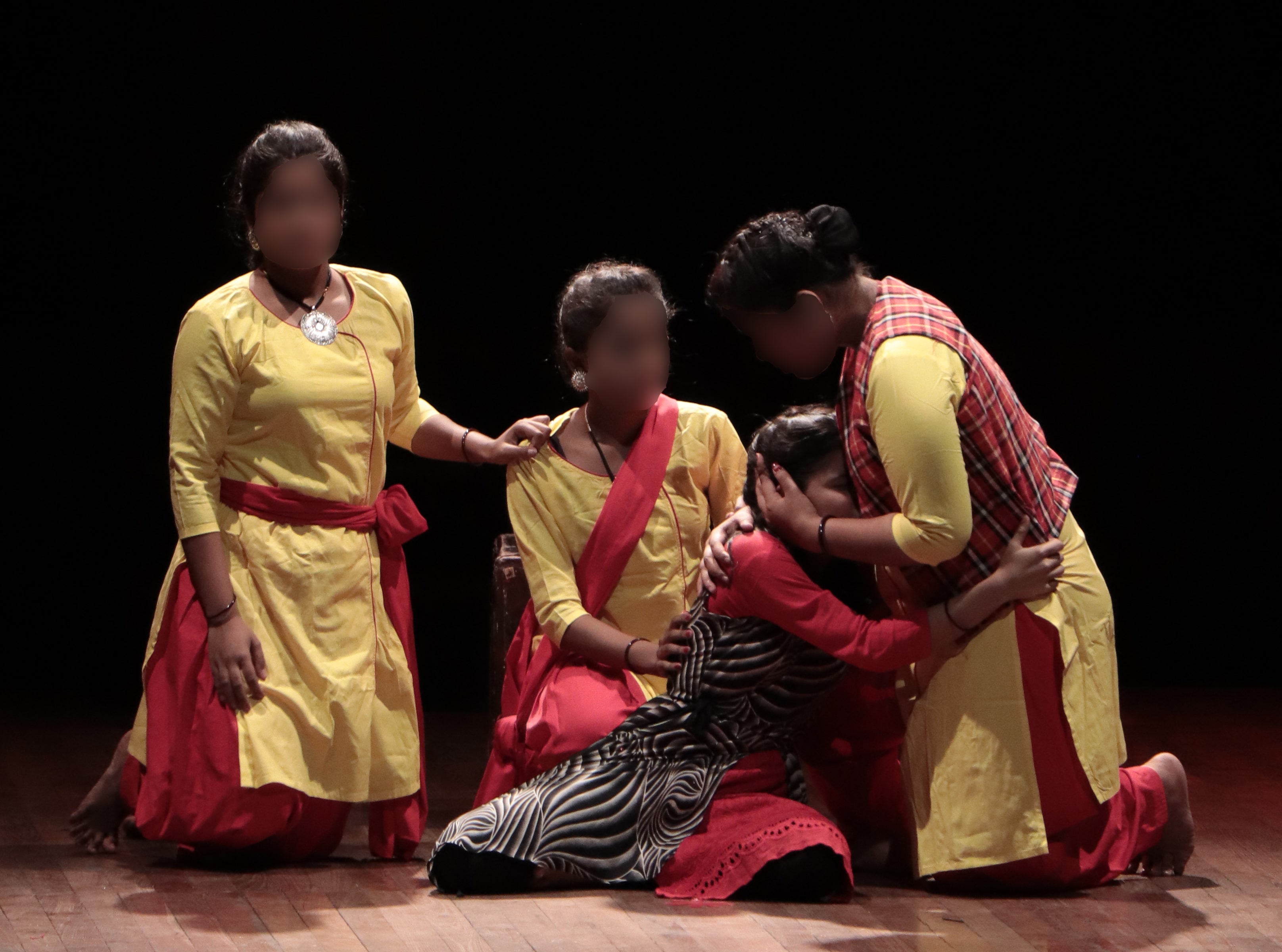 A young woman being embraced by three other women. 