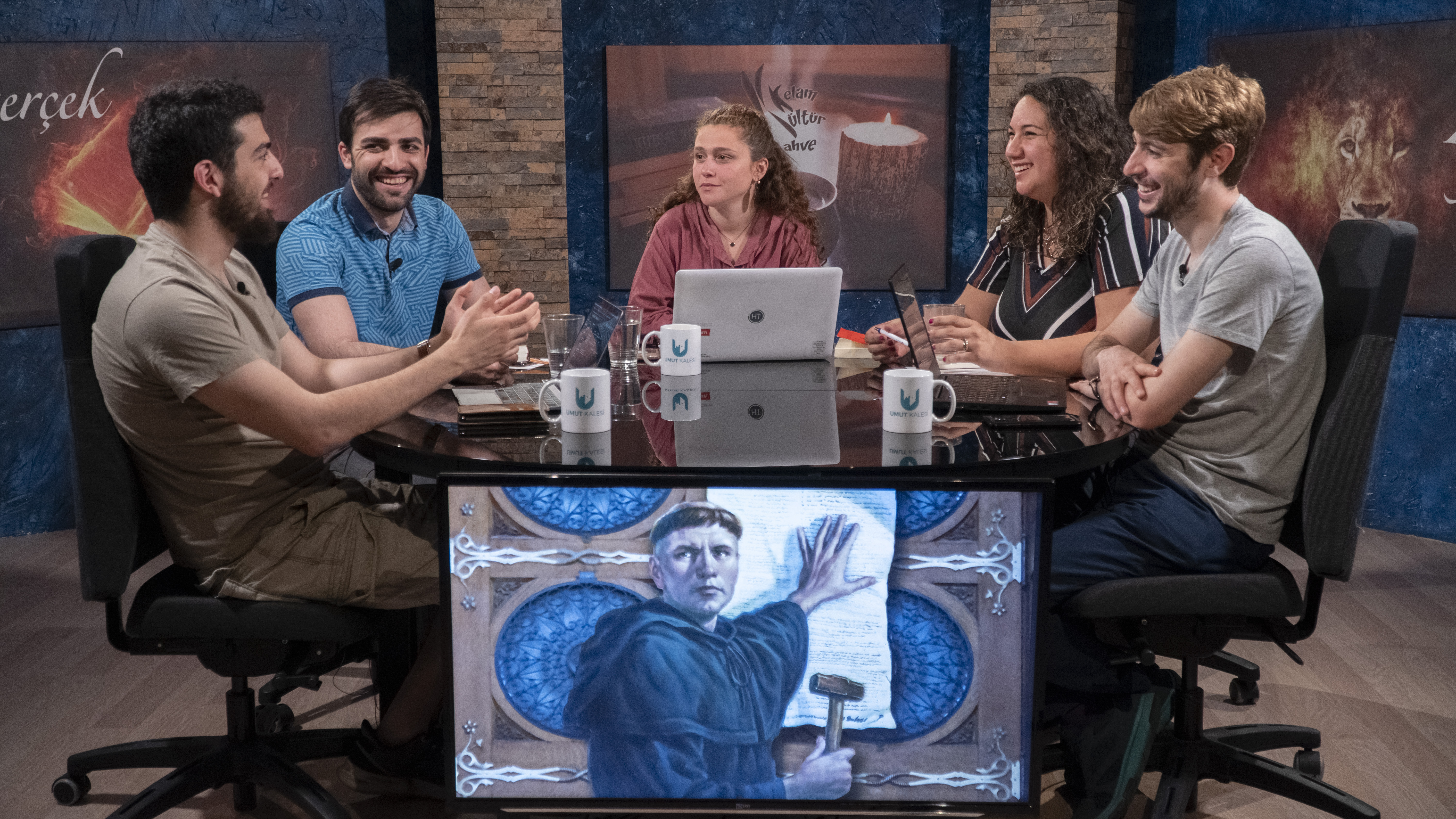 A group of five people sitting around a table, talking. 