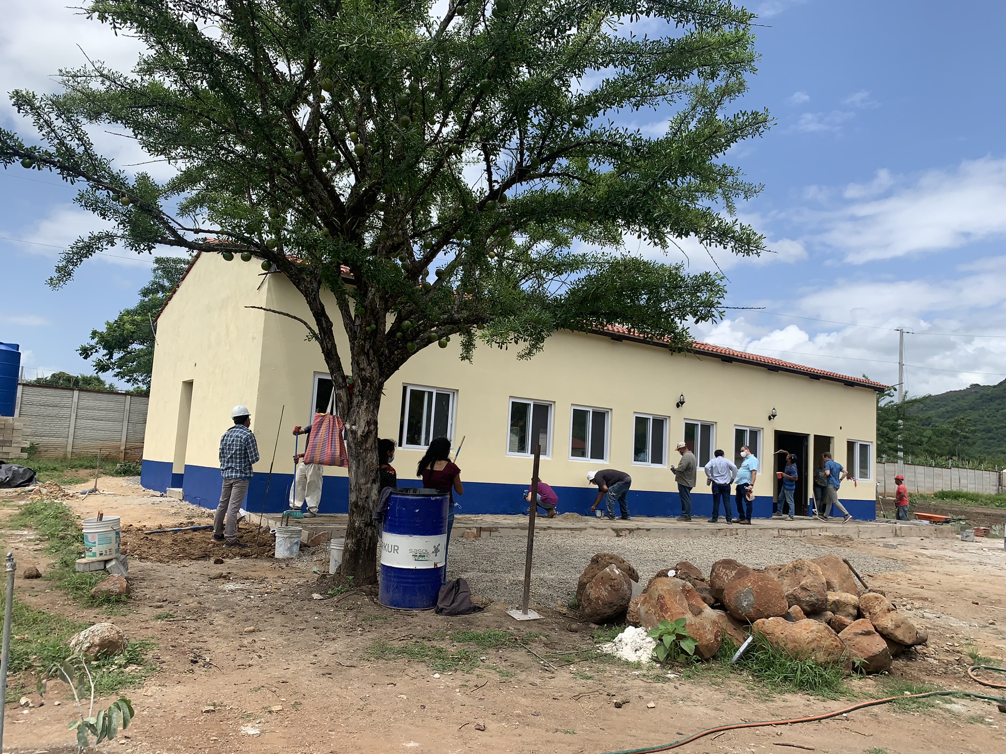 A group of construction workers working outside a large community building. 