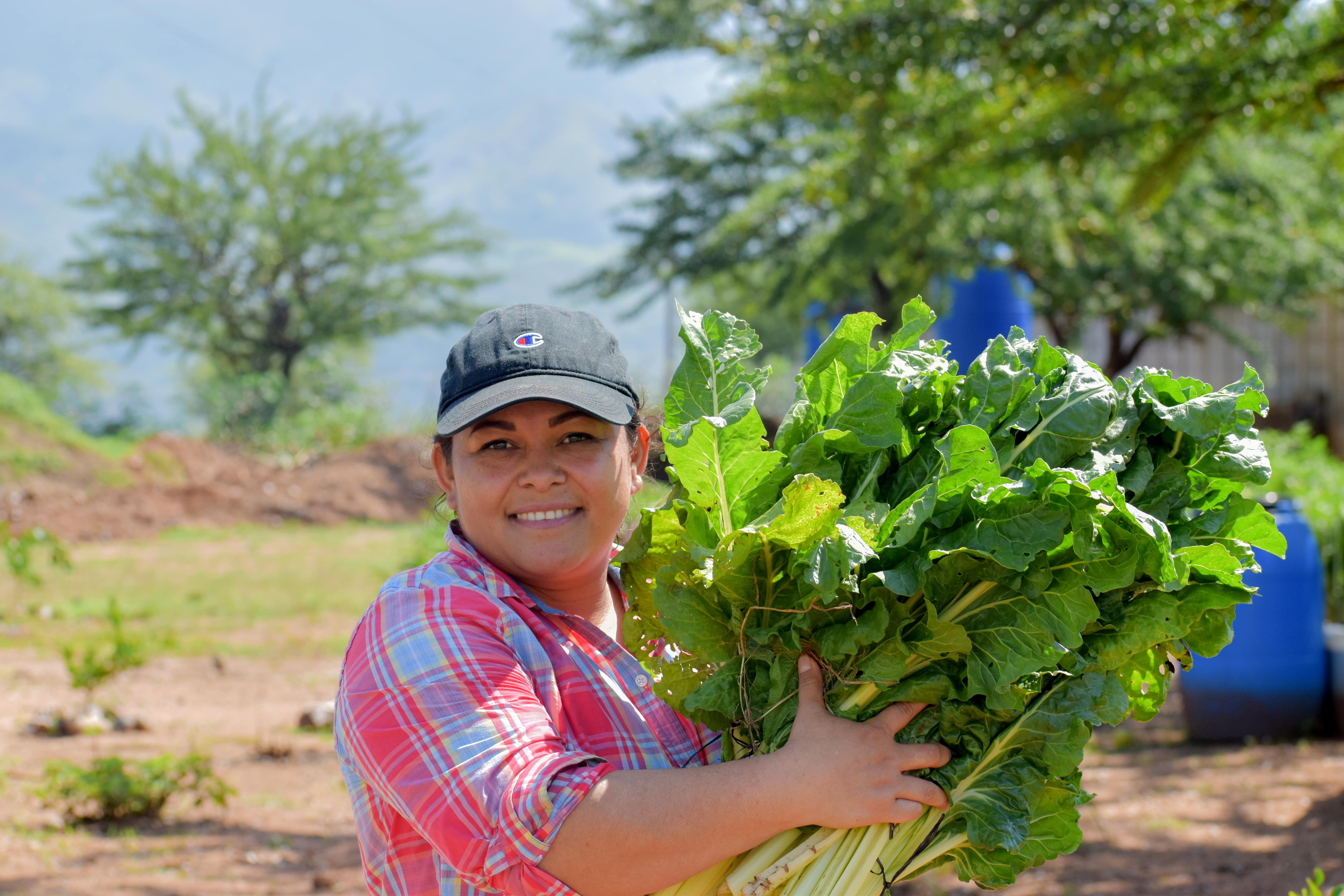 A woman holding crops smiling at the camera 