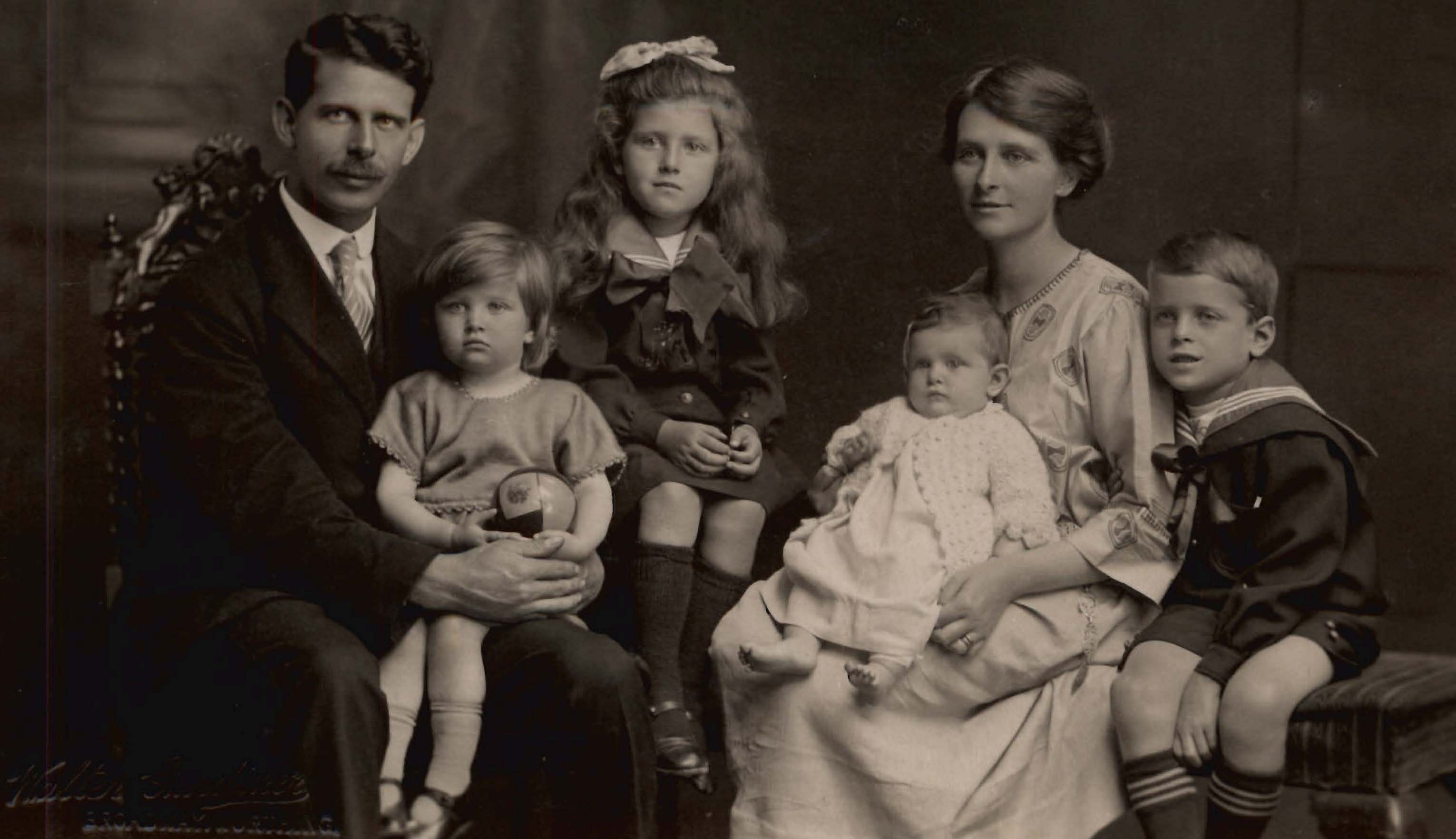 A vintage family portrait featuring a mother, father, and their four young children.