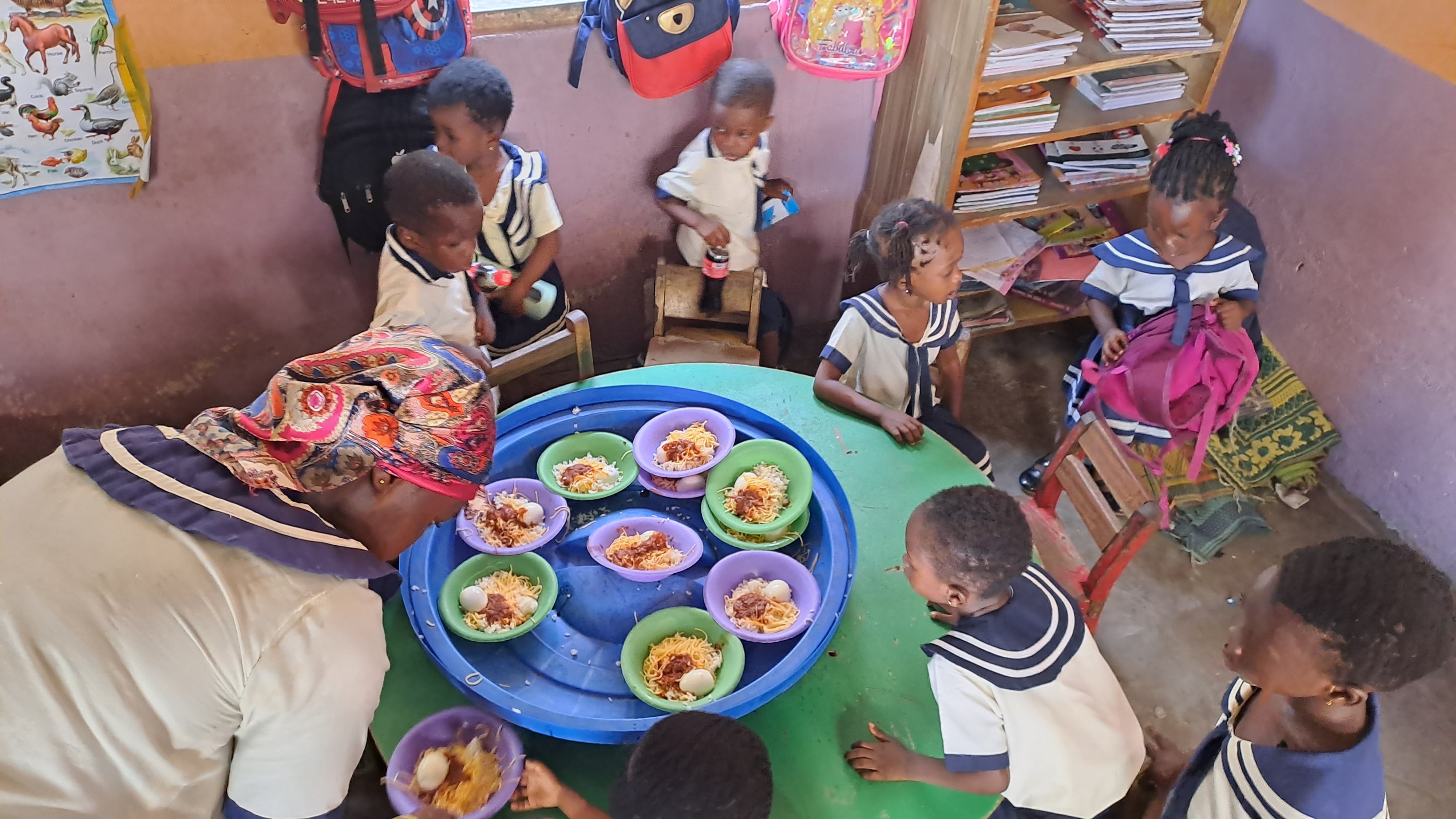 A group of young children sharing food around a table at school 