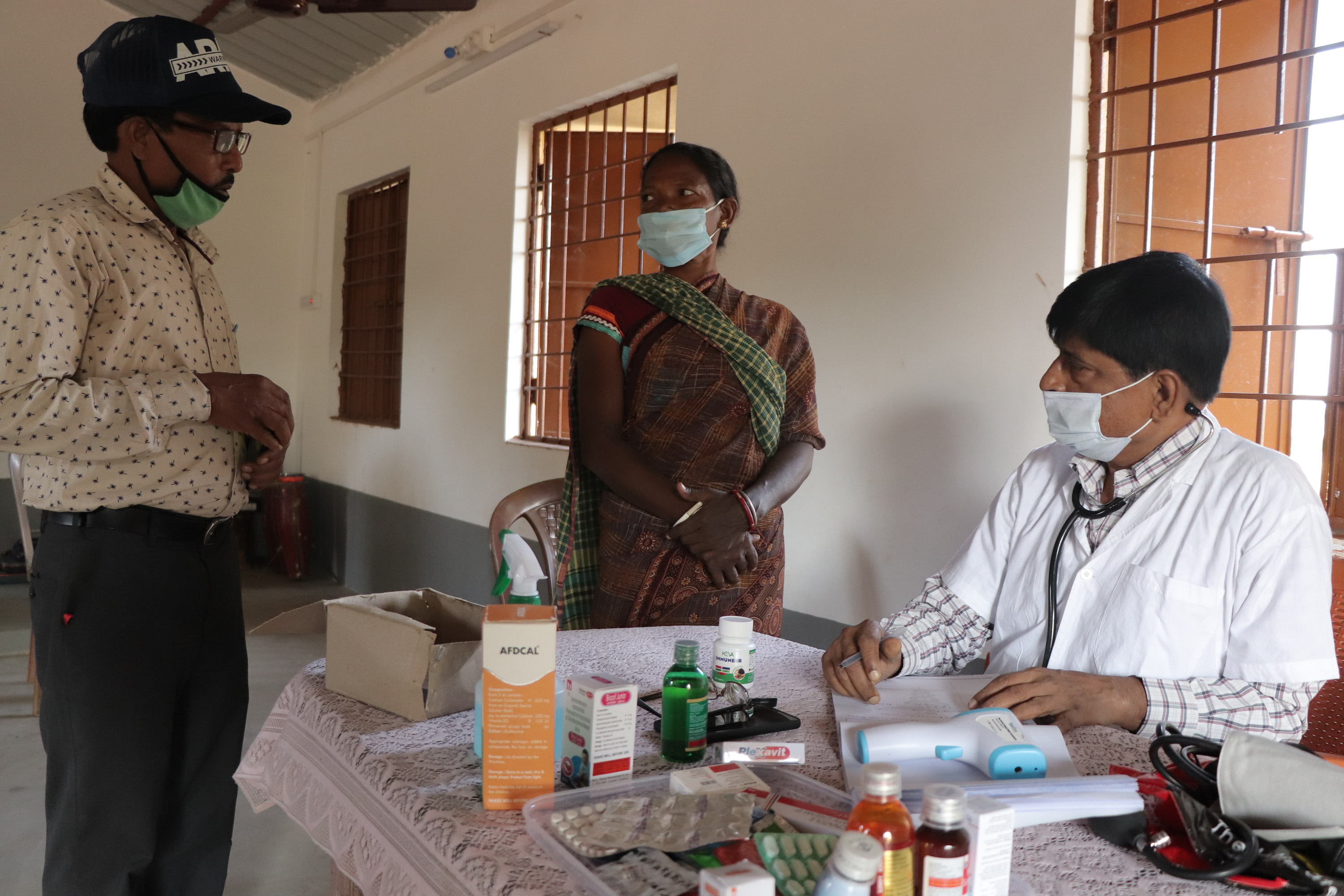 doctors standing around a table, talking to a patient. 