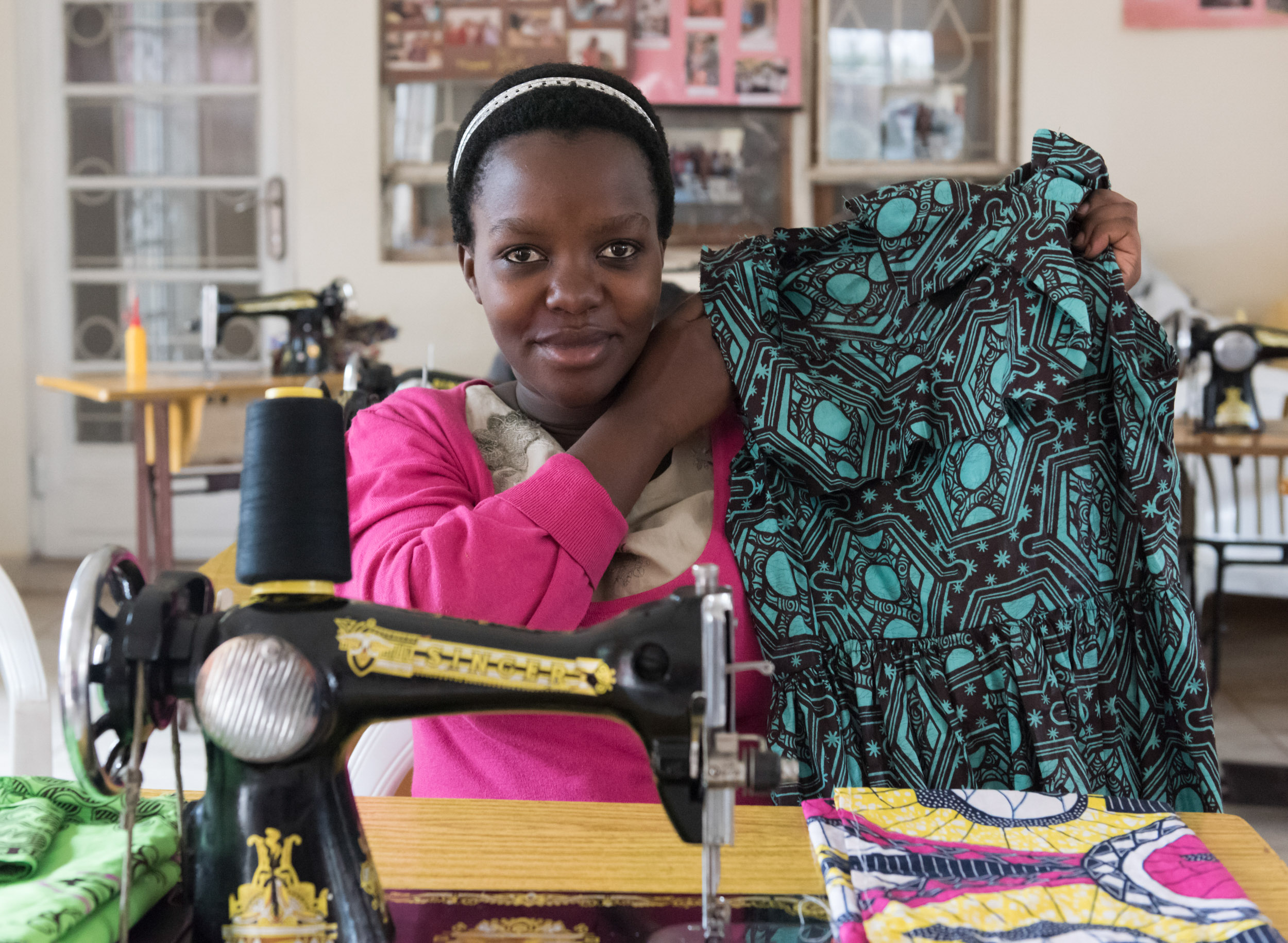 a young woman holding up a garment she made to the camera. 