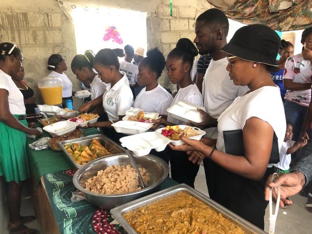 A group of people lining up for food at a canteen 