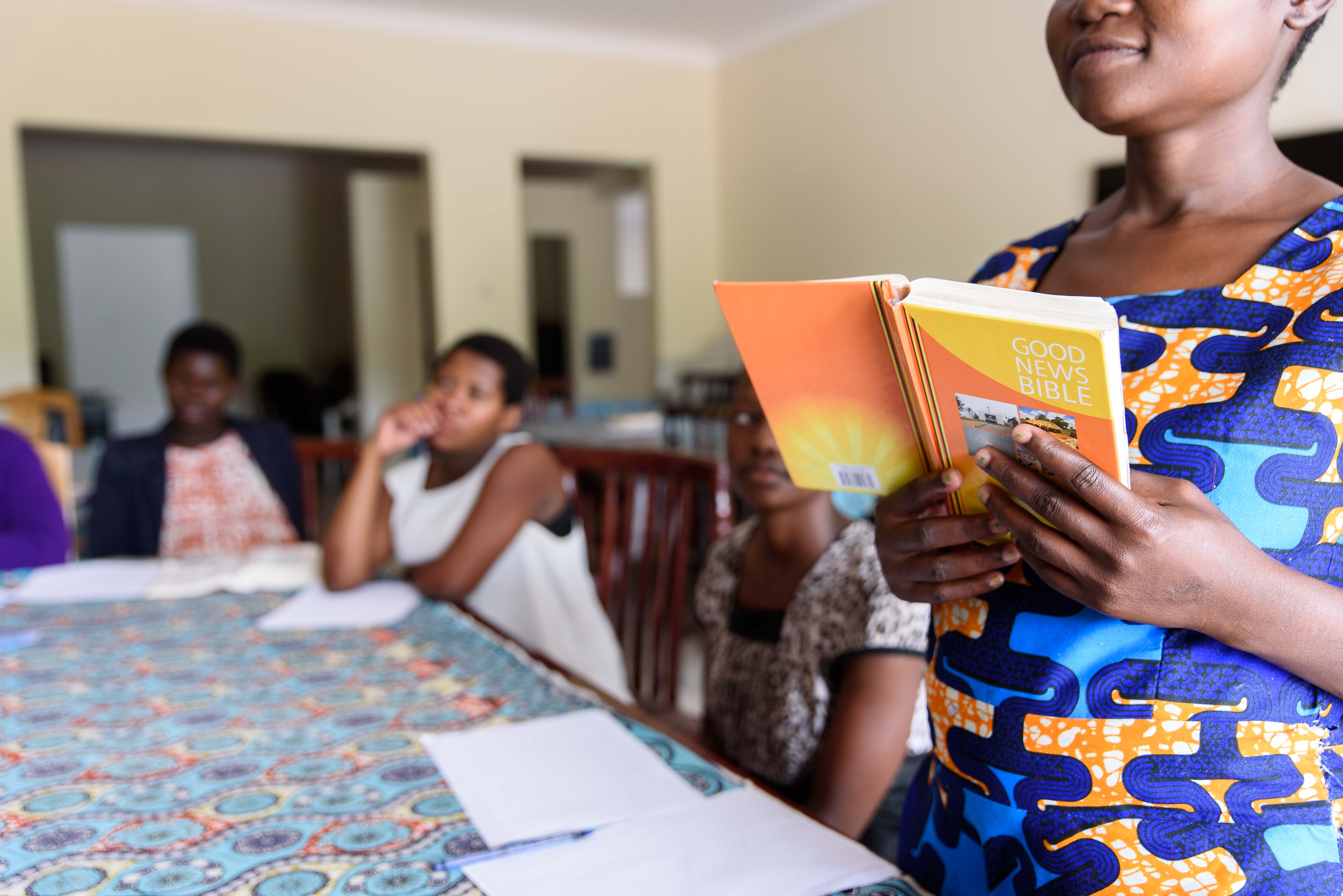 a woman reading the bible to a group at church