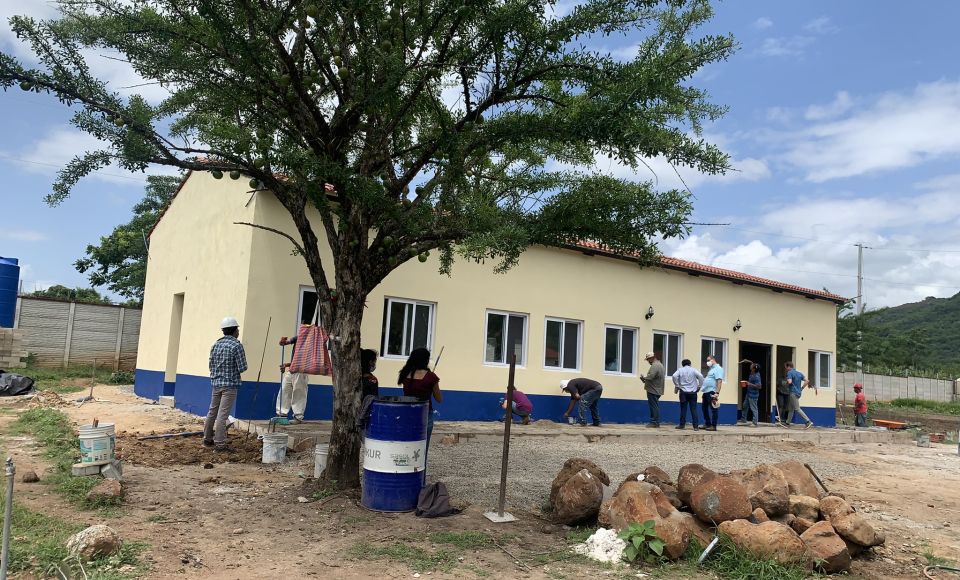 A group of construction workers working outside a large community building. 