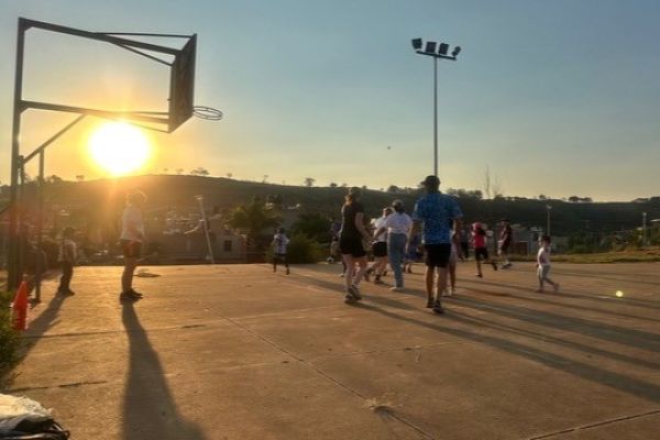 Children, young people and adults taking part in an outdoor sports activity on a court in Mexico at sunset