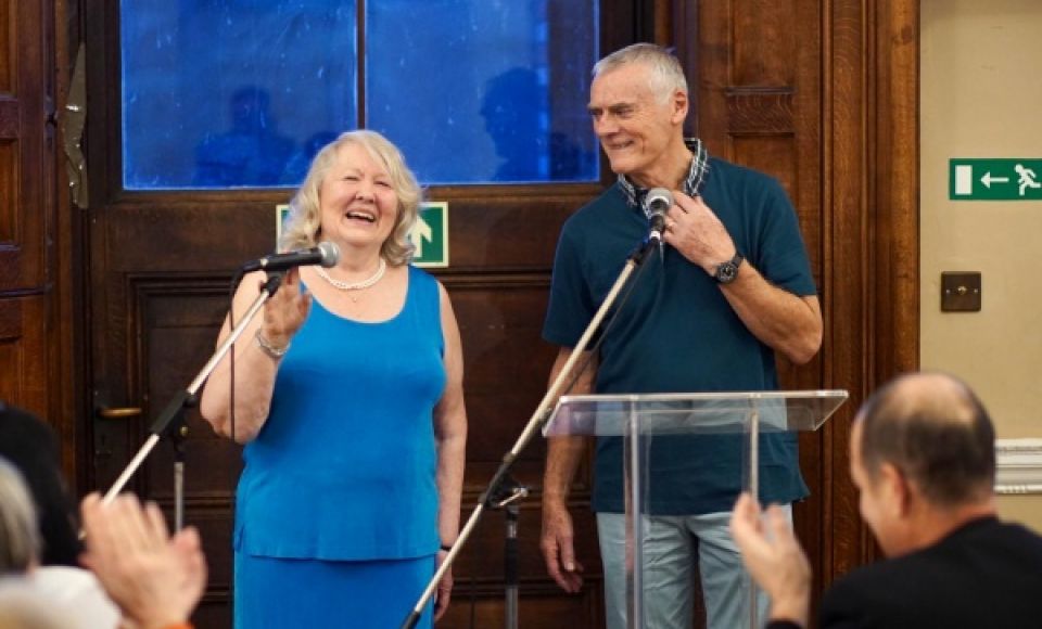 An older man and woman giving a speech at church. 