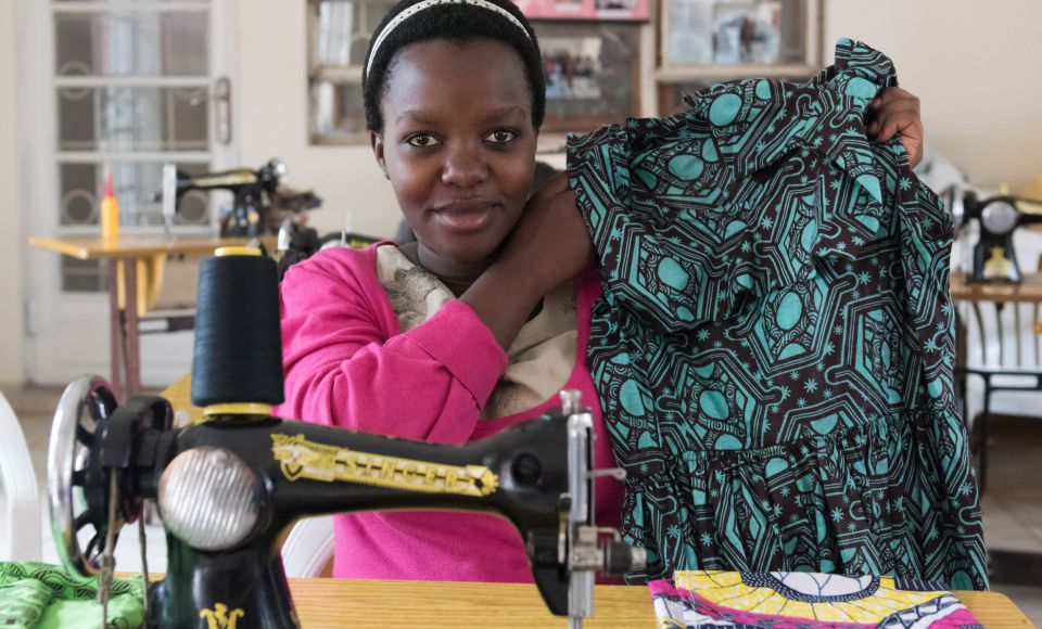 a young woman holding up a garment she made to the camera. 