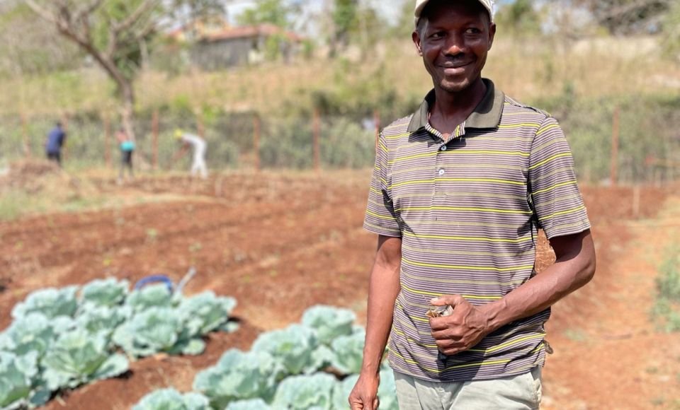 One man, looking into the camera, whilst working on a farm. 