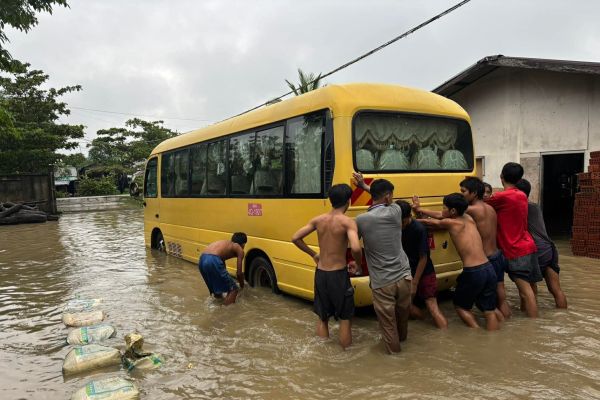 Young people helping push a yellow bus through floodwater at Word of Hope