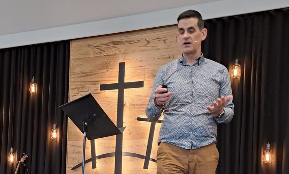 Andrew Yelland preaching gospel on stage at church 