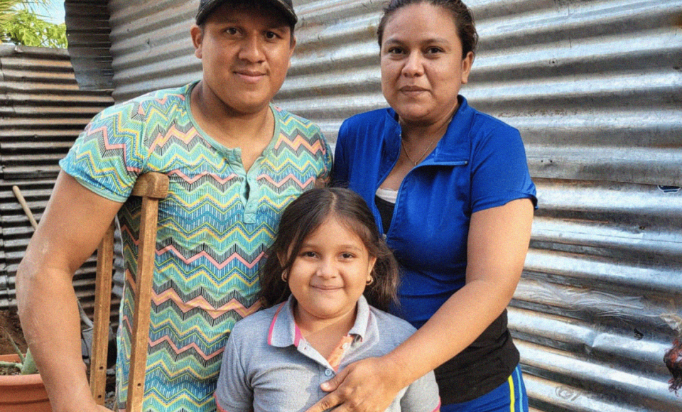 A young family smiling at the camera 