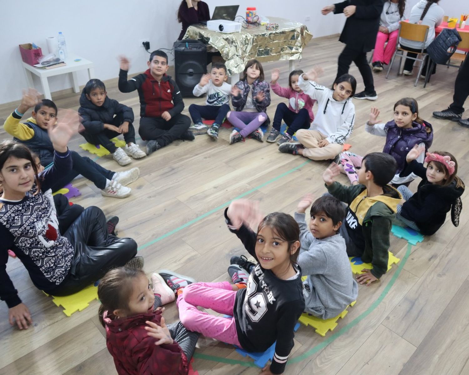 A small classroom of children holing up their art to the camera