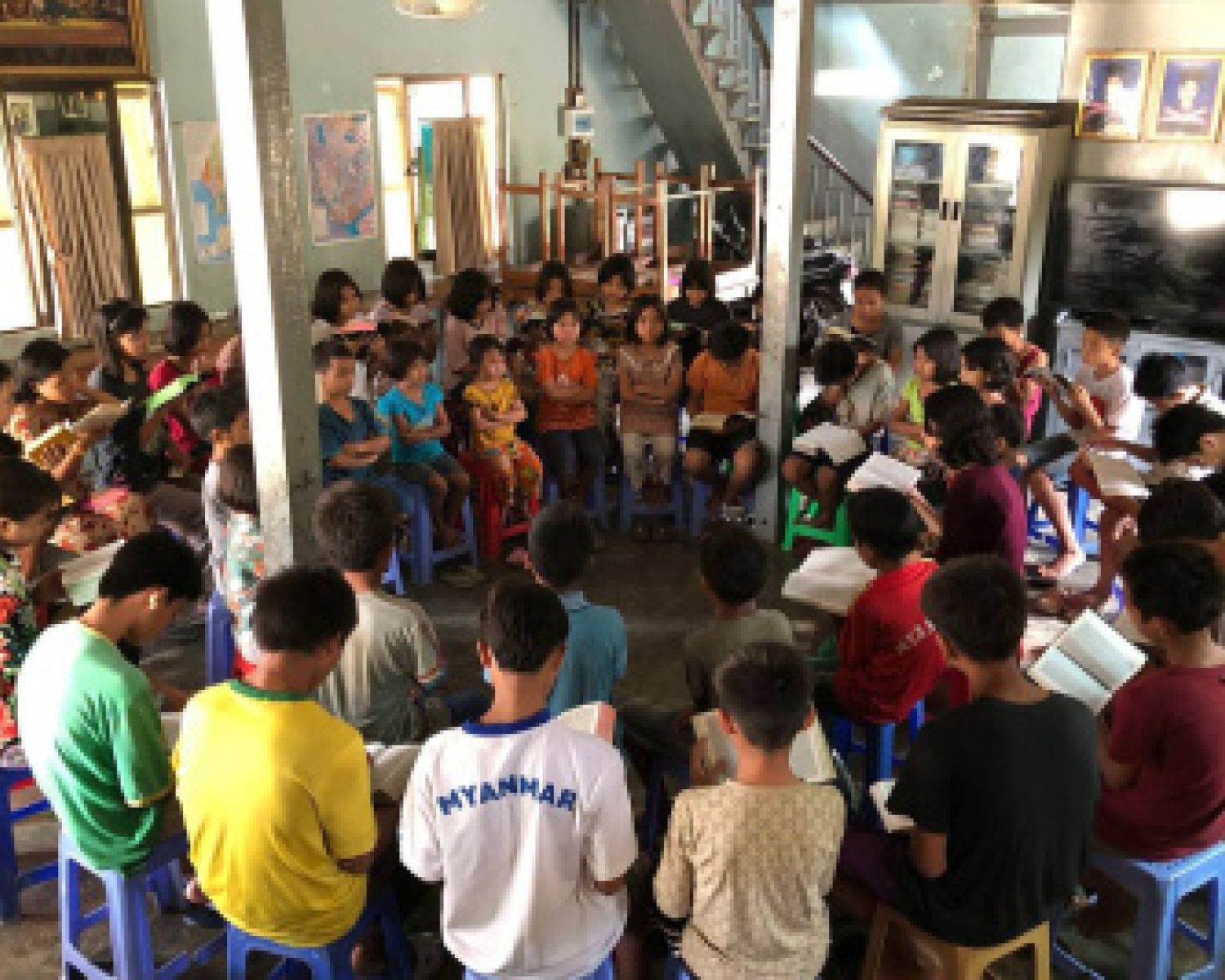 A large classroom sitting in a circle reading to one-another 