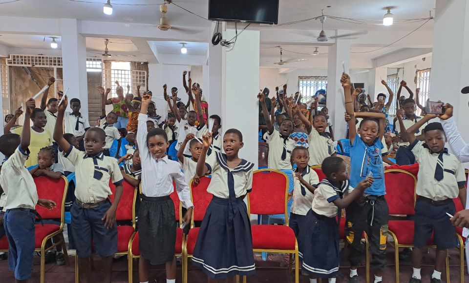 A large group of children raising their hands whilst attending a church ceremony. 