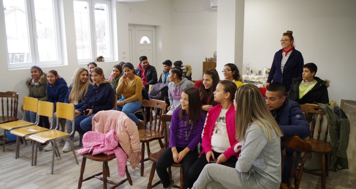 A large classroom sitting in a circle reading to one-another 