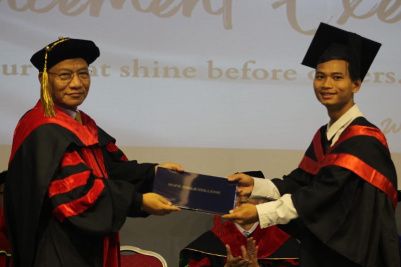 A young graduate, shaking hands with their teacher at the graduation ceremony.