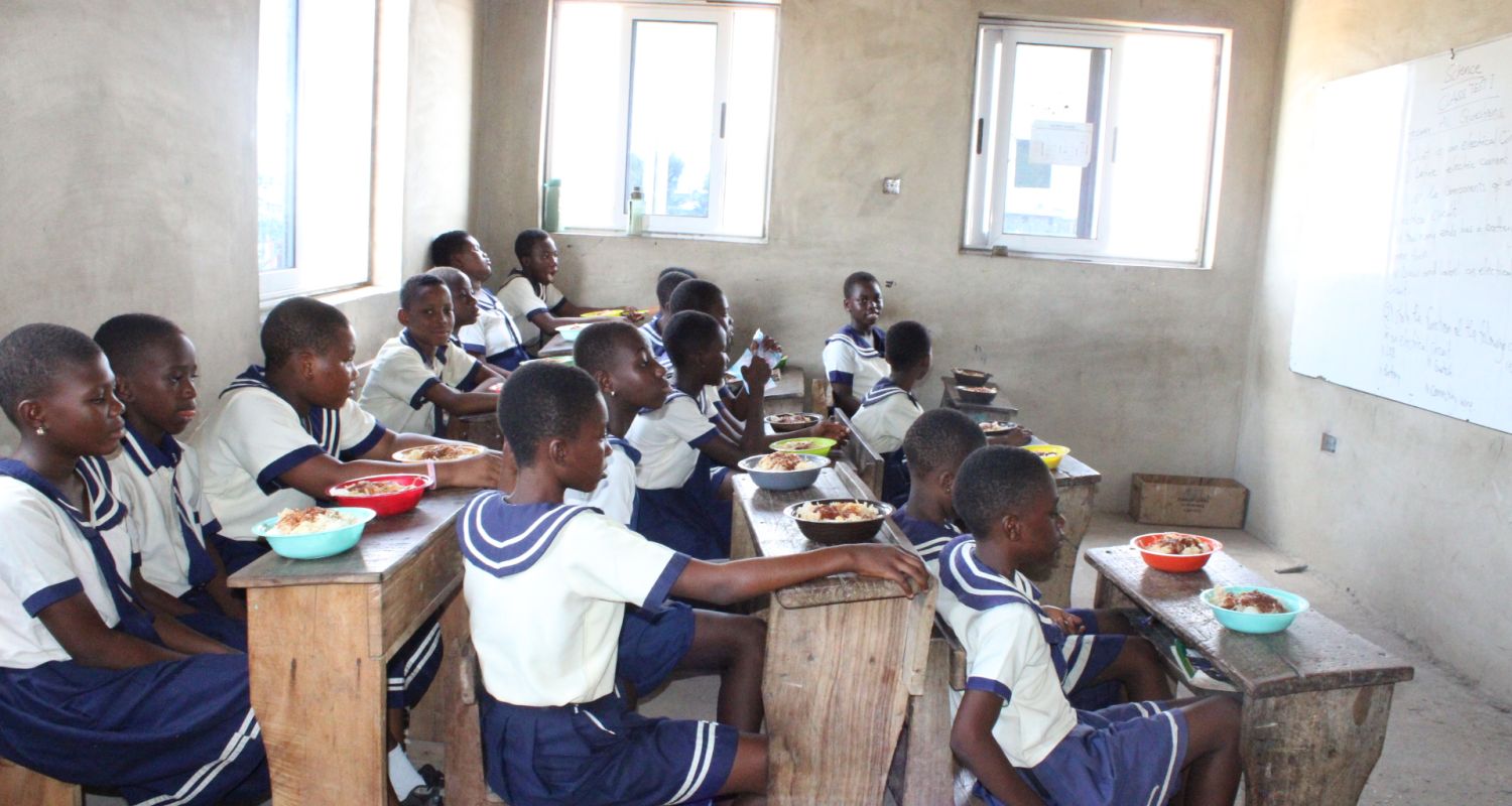 A classroom of children holding up their art to the camera. 