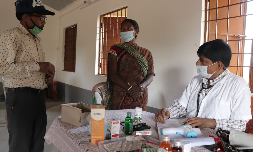 doctors standing around a table, talking to a patient. 