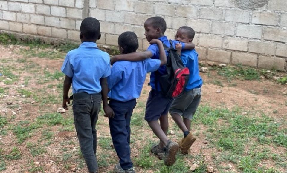 Four children embracing each other at school.
