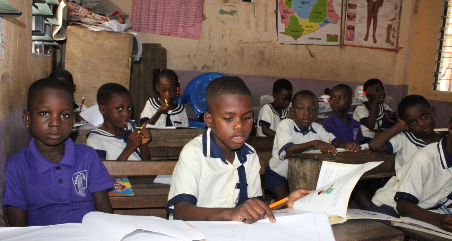 A large classroom sitting in a circle reading to one-another 