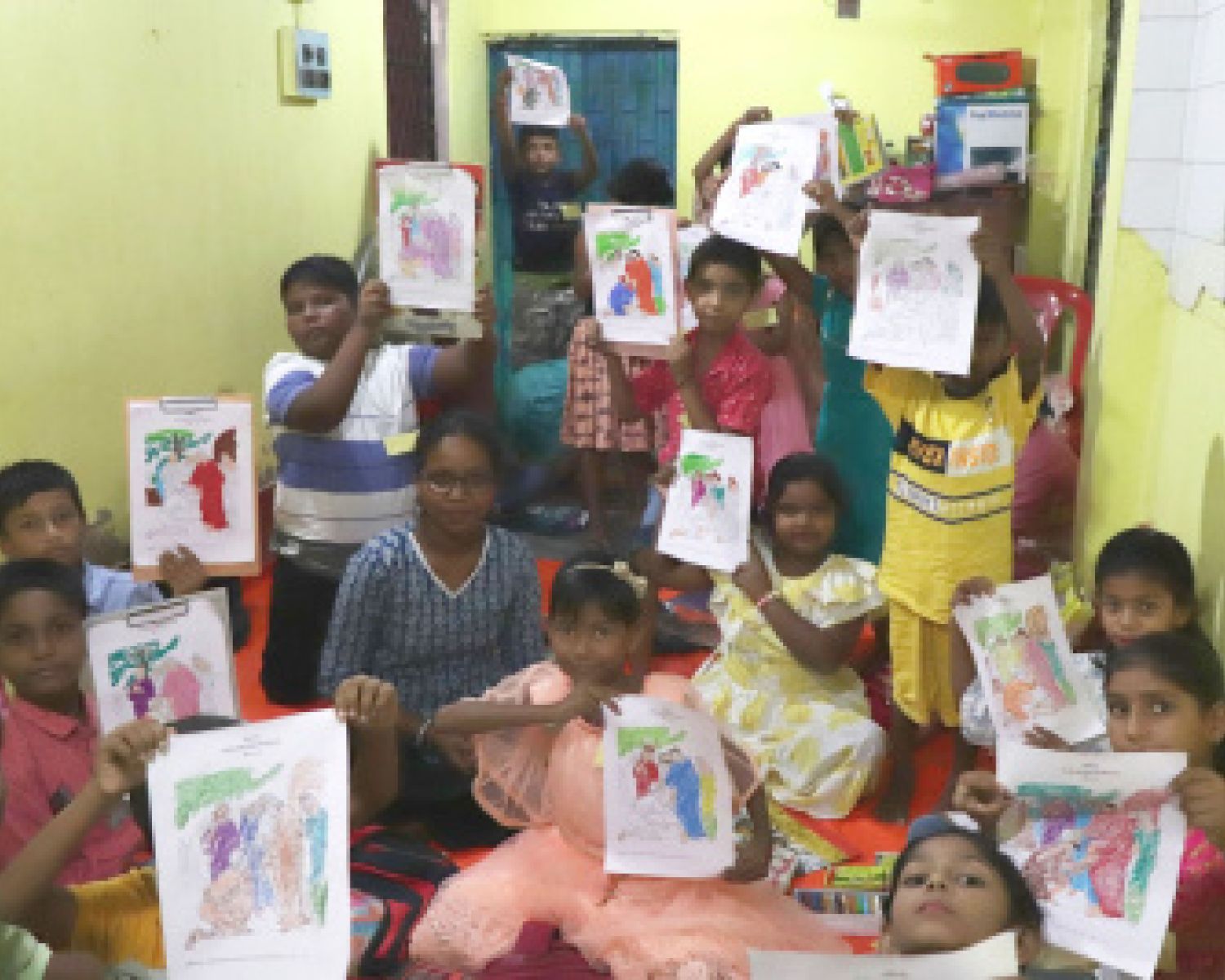 A small classroom of children holing up their art to the camera