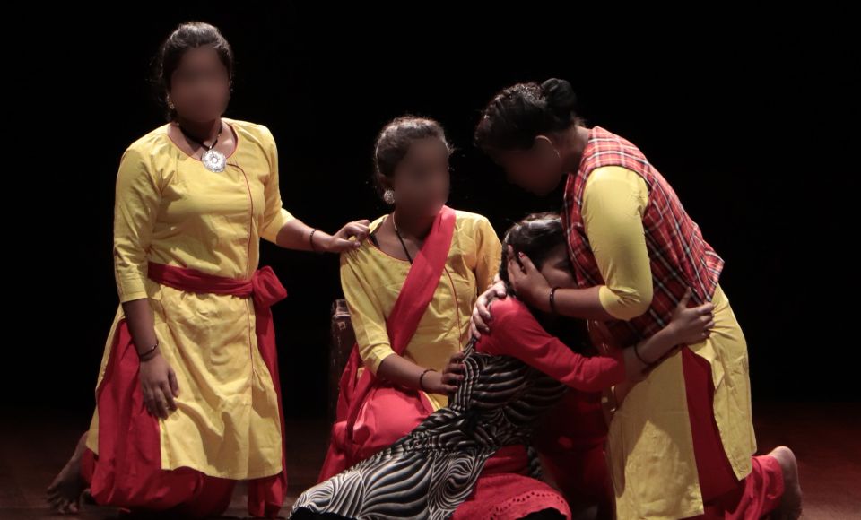 A young woman being embraced by three other women. 